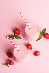 A glass of fresh strawberry smoothie on a pink background. Summer drink shake, milkshake and refreshment organic concept.