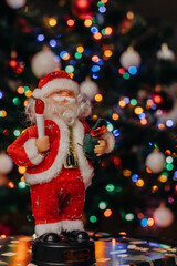 Toy Santa Claus with a bag of gifts in his hands on the background of festive Christmas lights. Figurine of Santa Claus. bokeh. Christmas. New Year