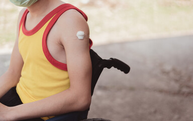 Arm of young man with disability cotton pads and plasters after vaccination, Boy wearing a mask in...