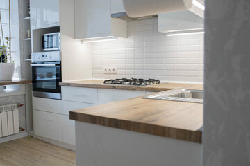 Fototapeta na wymiar white kitchen, white cabinets and solid wood worktop, gas stove and faucet.