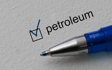 check mark on the word petroleum and blue pen. Closeup, concept
