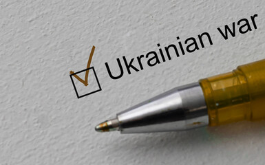 Fototapeta premium check mark on the word ukrainian war and pen. Closeup, concept