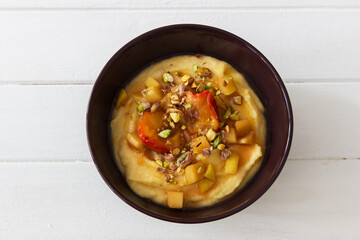 Sweet polenta porridge with coconut milk and fruit nuts topping.