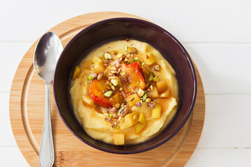 Sweet polenta porridge with coconut milk and fruit nuts topping.