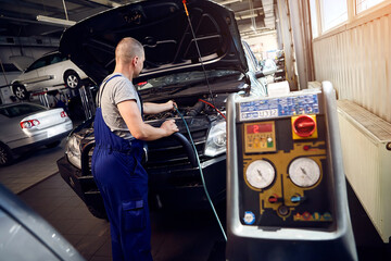 Mechanic checks air conditioning system in car auto service