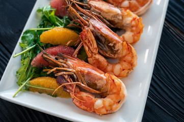 Grilled tiger prawns or shrimps with orange grapefruit and greens on a plate
