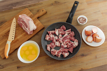 Meat cooking. Pork, eggs, salt on a wooden table, cutting board with a knife. Raw chopped meat in a frying pan