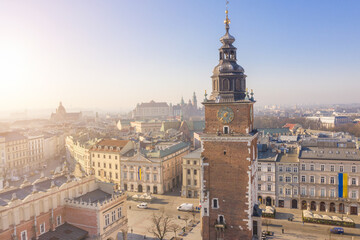 Fototapeta premium Town Hall Tower in Krakow Poland. Aerial view from above. Main Square Rynek Główny. Morning sunny soft light. Drove photo from above. symbol of the city’s power and prestige. Ukrainiane flage 