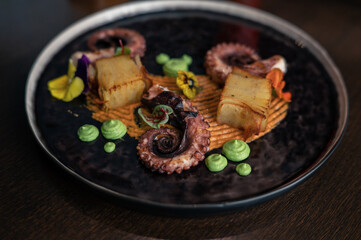 Octopus with potatoes on pea mash decorated with edible flowers