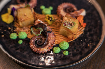 Octopus with potatoes on pea mash decorated with edible flowers