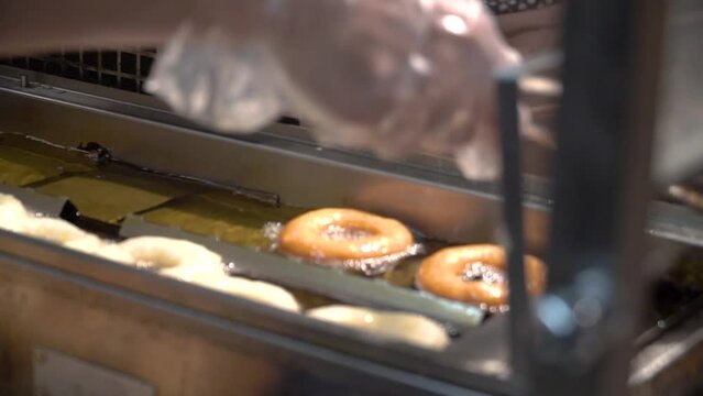 On the assembly line, donuts are fried in oil. They float in an oil vat.