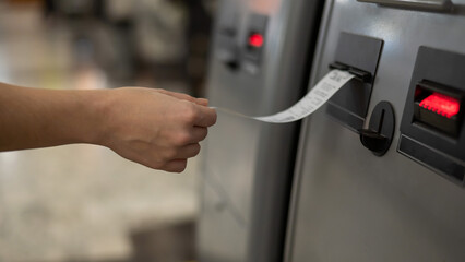 A woman takes a printed check from an ATM. 