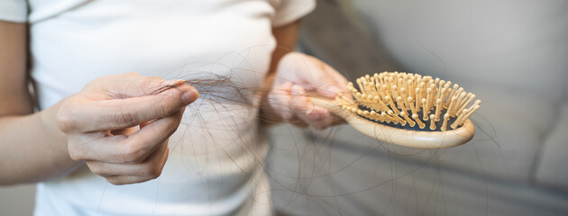 Hair fall problem concept. Shocked Asian woman looking at many hair lost in her hand and comb.