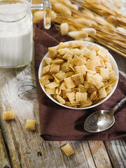 Quick whole grain breakfast. On a wooden table are cereal pads in a bowl, a jug of milk. bunch of cereals. Solar lighting. There is no one in the photo. Traditional American breakfast. Organic food.