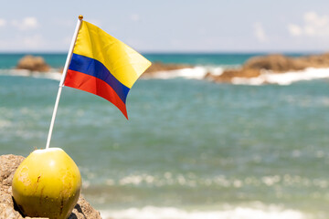 Colombia flag protruding from the coconut and fluttering in the background of the beach and the...