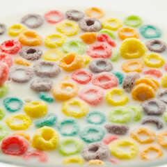 Quick breakfast cereals. Colored fruit rings in milk. Healthy baby food, school breakfasts, healthy lifestyle, healthy food. Abstraction. Close-up. Food background.