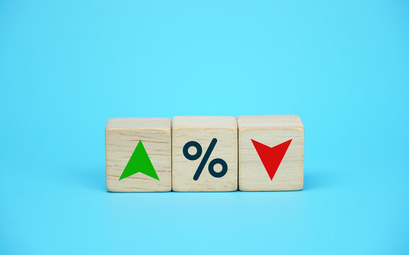 Interest rate financial and mortgage rates concept. Wooden cube block with icon percentage, symbol arrow up and down. blue background.	