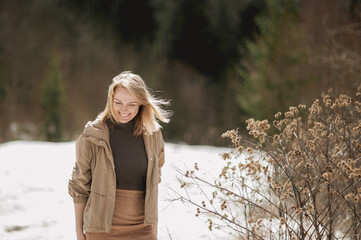 Portrait of a beautiful smiling blonde woman in a beige jacket walking on a sunny day in early spring. place for text