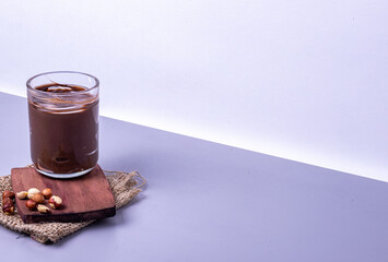 Jar of hazelnut paste on a wooden stand on a gray background