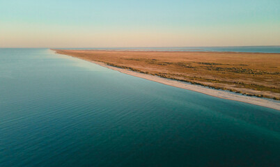 Panoramic landscape of sandy beach and clear blue sea water at sunset. Banner image seascape from air. Dzharylhach island, Ukraine