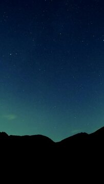 Timelapse of stars over silhouette mountains at night