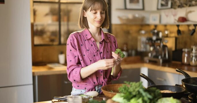 Young woman making salad while cooking healthy food in the kitchen at home. Healthy lifeatyle and wellness concept