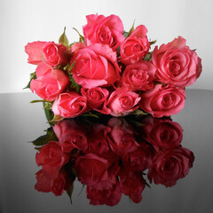 Spiegelung von mehreren roten Rosen auf grauem Hintergrund 
