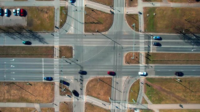 4K hyperlapse top view of a busy crossroad with traffic lights in a city. Autumn yellow lawns near the crossroads. Hyper laps taken from a DJI drone from a bird's eye view.