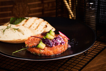 Tartare from salmon with bread on table in restaurant.