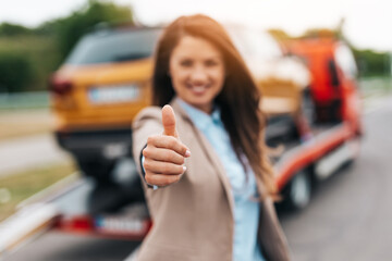 Elegant middle age business woman is happy and satisfied with fast and reliable towing service for...