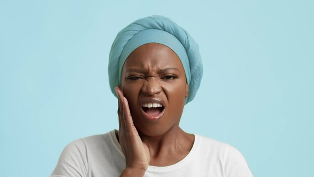 Unhappy Black Woman Suffering From Toothache Touching Cheek, Blue Background