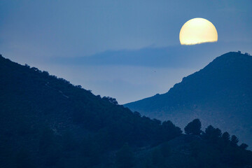 Fototapeta premium Sun disk between mountains at sunset