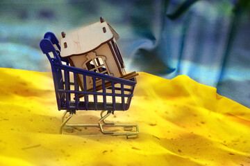 A wooden small house in baskets from a supermarket stands on the sand against the backdrop of the...