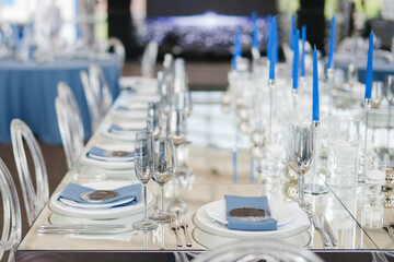 Coziness and style. Modern event design. Table setting at wedding reception. Floral compositions with beautiful flowers and greenery, candles, laying and plates on decorated table.
