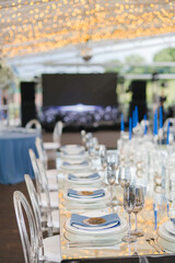 Coziness and style. Modern event design. Table setting at wedding reception. Floral compositions with beautiful flowers and greenery, candles, laying and plates on decorated table.