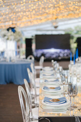 Coziness and style. Modern event design. Table setting at wedding reception. Floral compositions with beautiful flowers and greenery, candles, laying and plates on decorated table.