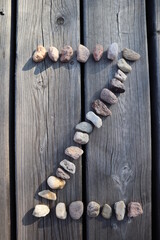 Letter Z from small river stones. Capital letter on wooden background. Stone alphabet.