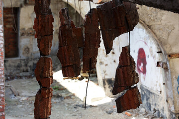 Fragmenty muru i cegieł z rozwalonej fabryki widoczne wiszące druty.