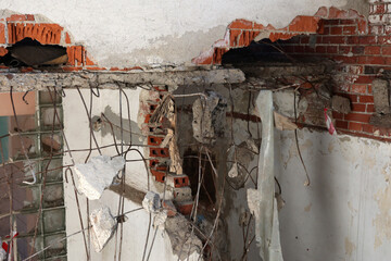 Fragmenty muru i cegieł z rozwalonej fabryki widoczne wiszące druty. - obrazy, fototapety, plakaty