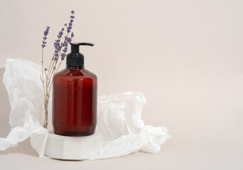 Mockup Spa body cosmetics in brown bottles gel, shower soap, shampoo with a pump on a concrete podium stand with lavender branches on a beige background and crumpled paper decoration.