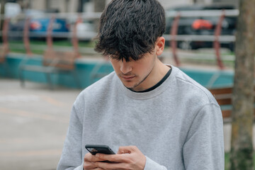 urban young man in the street typing on the mobile phone