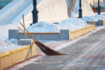 Winter morning on the city embankment in the new year. Hand tool for snow removal. Brooms near...