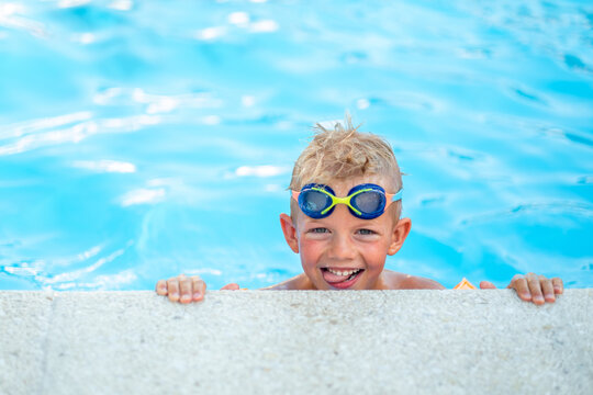 Portrait smiling boy in swimming pool, child in swimming glasses and inflatable sleeves. Summer travel hotel vacation or classes