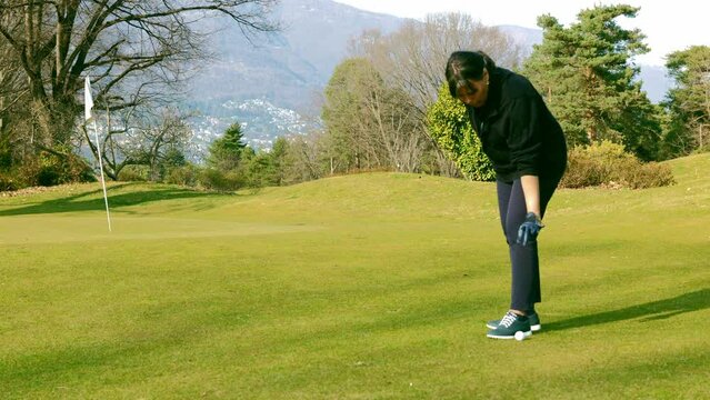Golfer Dropping the Golf Ball on Fairway in a Sunny Day in Switzerland.