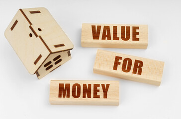 On a white surface, a wooden toy house and blocks with the inscription - Value for Money
