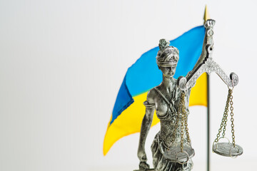 On a white background, the national flag of Ukraine and a sculpture of the goddess of justice -...