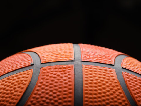 Macro shot. On a black background, details of a basketball. Sports, sports games, healthy lifestyle, training, stadium, gym. There is free space to insert. There are no people in the photo.