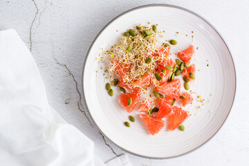 Fresh salad of grapefruit, clover and alfalfa sprouts and pumpkin seeds on a plate on the table. Organic vegetarian detox food. Top view. Close-up