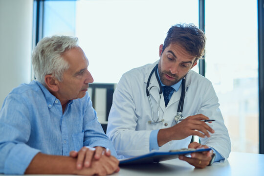 Every patient should have a clear understanding of their diagnostic. Shot of a handsome doctor going over some paperwork with a male senior patient in a clinic.