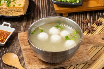cod ball soup in a steel bowl isolated on wooden board side view on table taiwan food